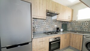Eine Küche mit Holzschränken, einem Edelstahlkühlschrank, einem eingebauten Ofen und einer Waschmaschine.