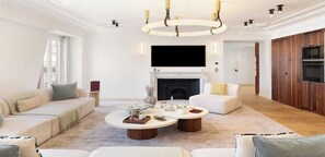 A spacious living room with a fireplace, sofas, a coffee table, and a TV. - Fully Air-Conditioned,View Of The Eiffel Tower-Duplex With Services La Madeleine (Paris)