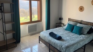 Une chambre à coucher avec un lit, une fenêtre avec des rideaux, un radiateur, une étagère et un élément de décoration murale.