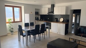 Une cuisine moderne avec des meubles blancs, un plan de travail noir et un coin repas comprenant une table et des chaises.