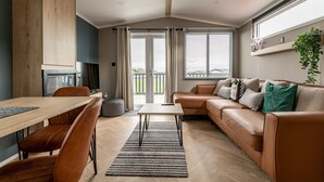 A modern living room with a wooden dining table, leather sofa, and a large window.
