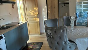 A modern kitchen with a built-in washing machine, a dining area with a table and chairs, and a colorful rug. - Getaway & wellness accommodation Massage Jacuzzi Sauna (Ravenel)