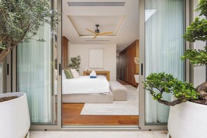 A modern bedroom with a bed, bedside tables, and a ceiling fan.