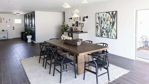 Un comedor con una mesa de madera, sillas negras, un tapete blanco y una obra de arte con un cactus en la pared.