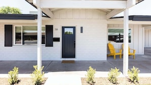 Una casa moderna con un porche cubierto, una puerta negra y el número 'T320' en la pared.