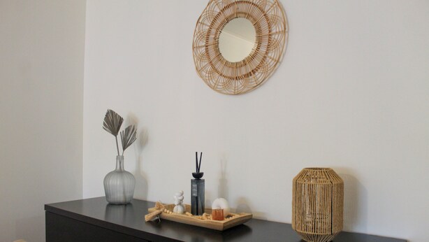 A dark-colored dresser with a mirror, a woven decorative piece, and a tray with various items. - Atlantic Central Apartment (Ponta Delgada)