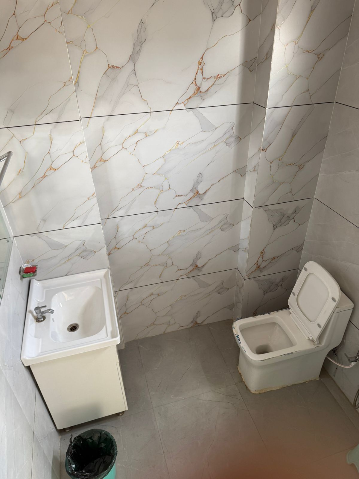 Un baño con lavamanos, inodoro y paredes con diseño de mármol.