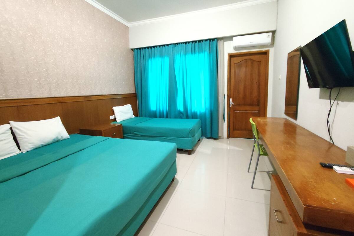 Habitación de hotel con dos camas, un escritorio, una silla, un televisor y una puerta.