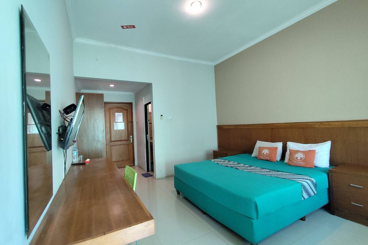 Un dormitorio con cama, escritorio, espejo y puerta.