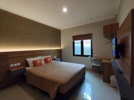 Un dormitorio con cama, mesitas de noche, escritorio, silla, televisor y ventana.