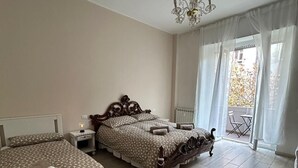 A bedroom with two beds, a chandelier, a window with sheer curtains, and a balcony. - Casagrande Milan (Milano)