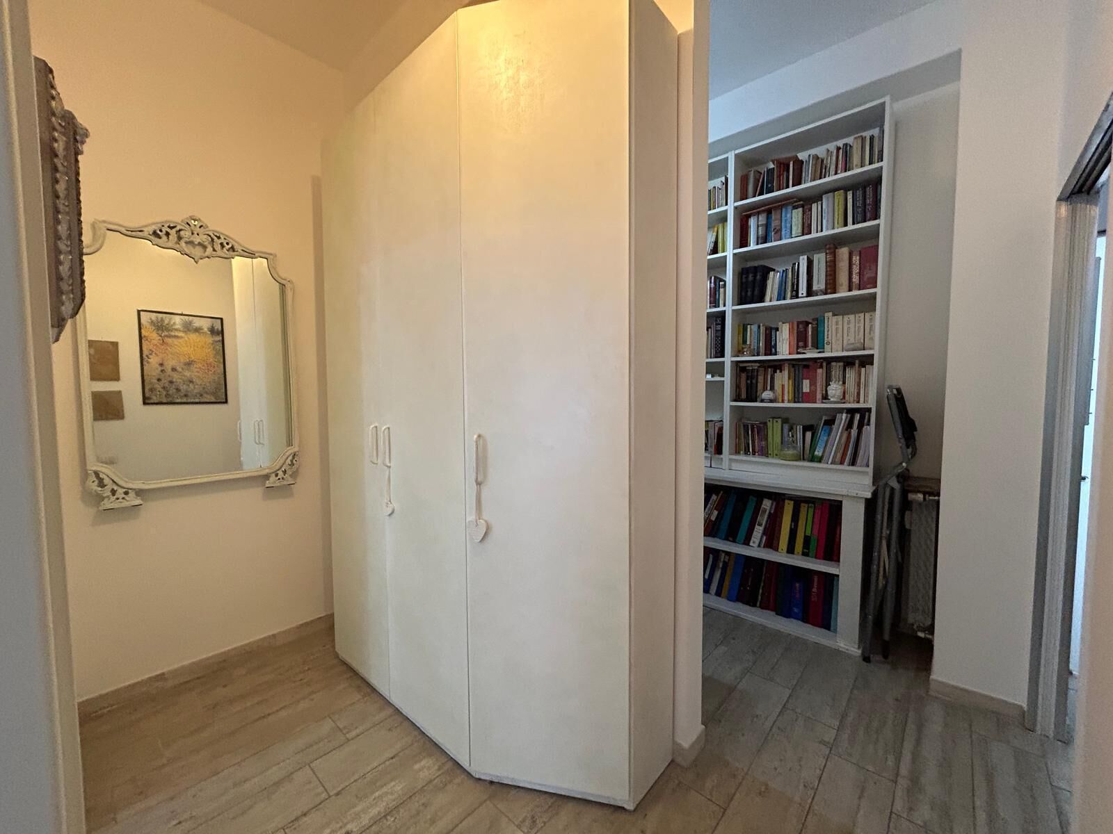 A room with a wardrobe, a mirror, and a bookshelf.