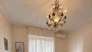 A room with two beds, a chandelier, a radiator, and a window with curtains. - Casagrande Milan (Milano)