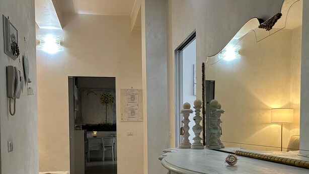 A hallway with a white marble counter, a small table, and a mirror. - Casagrande Milan (Milano)