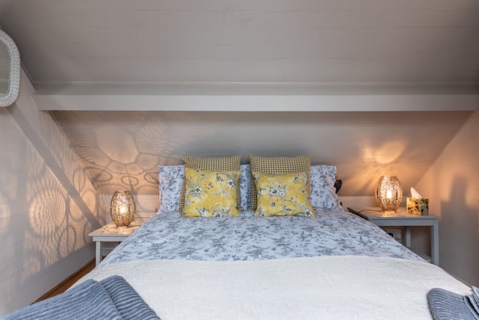 Une chambre à coucher avec un lit, deux tables de chevet et une lampe fixée au mur.
