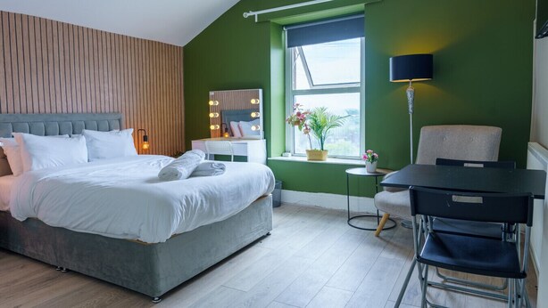 A modern bedroom with a bed, vanity, and a desk. - Praise Suite | Stylish Apartment • Parking • Wi-Fi (Barry)