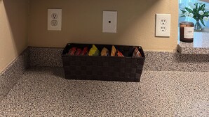 Eine Küche mit einer Arbeitsplatte, einem Schrank mit Weingläsern, einem Behälter und einer Kiste mit Snacks.