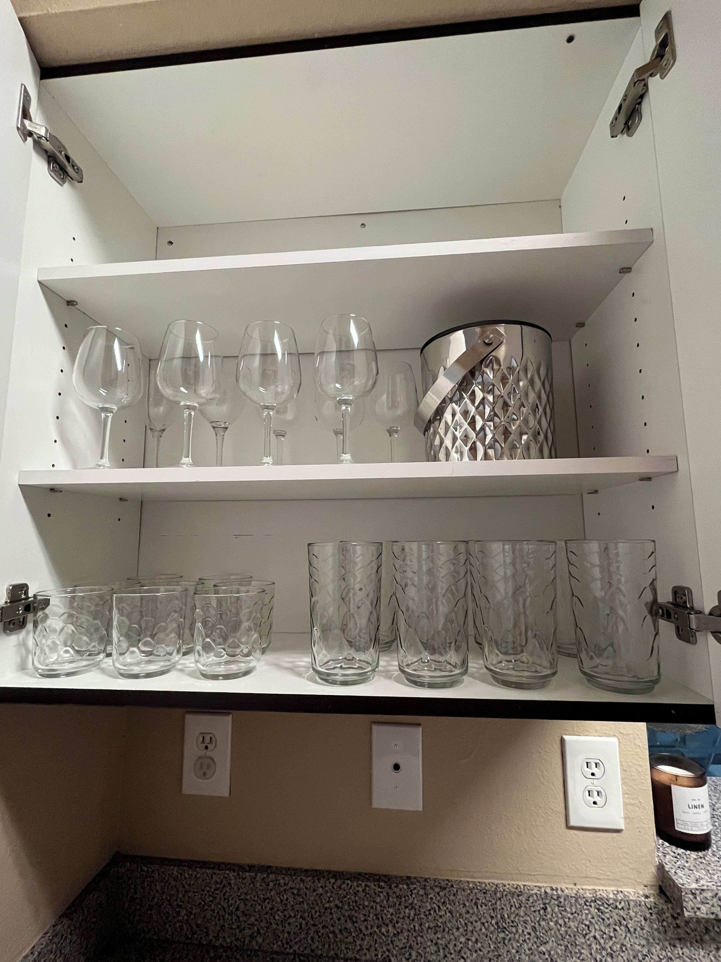 Une étagère de cuisine avec des verres à vin et des verres à cocktail.