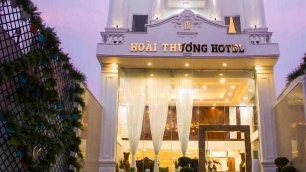 Ett hotell med en klassisk fasad, en framträdande entré med en trappa och en skylt med texten ”HOAI THUONG HOTEL”.