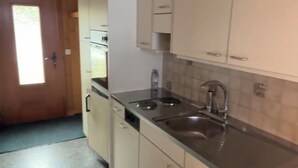 Een keuken met witte kasten, een RVS-gootsteen en een houten plafond.