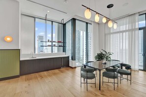 A modern kitchen with a large window, a dining area with a table and chairs, and a view of the cityscape. - New 1/1 Condo, Downtown Miami Area Cool Amenities (Miami)