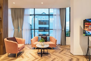 Quarto moderno com sofá, poltrona e uma pequena mesa com planta.