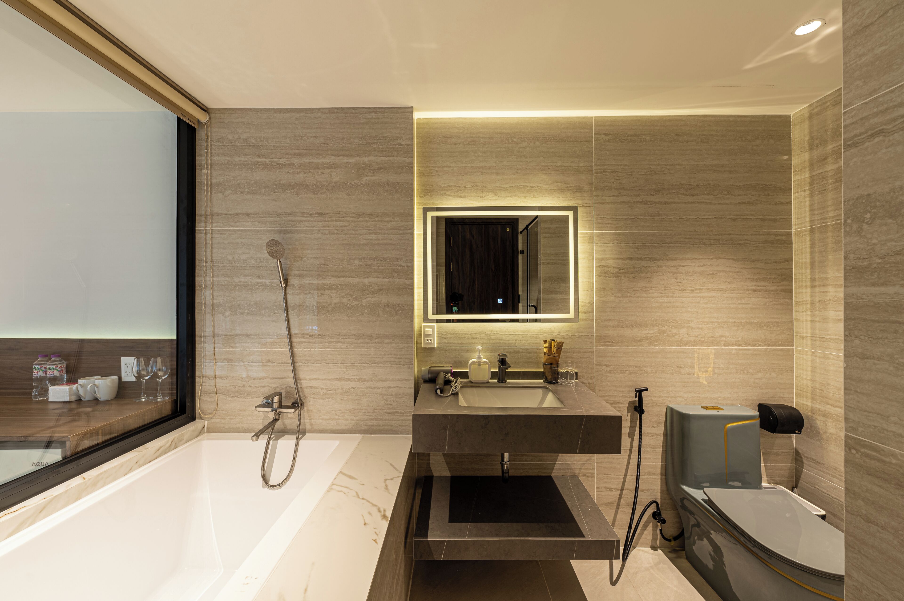 Une salle de bain moderne équipée d’une baignoire, d’une douche, d’un meuble-lavabo avec un miroir et d’une fenêtre.