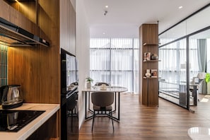 Una cocina moderna con comedor, paneles de madera y un amplio ventanal con cortinas translúcidas.