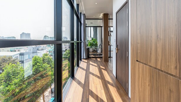 Ein modernes Interieur mit einem langen Korridor, großen Fenstern und Blick auf die Stadtlandschaft.