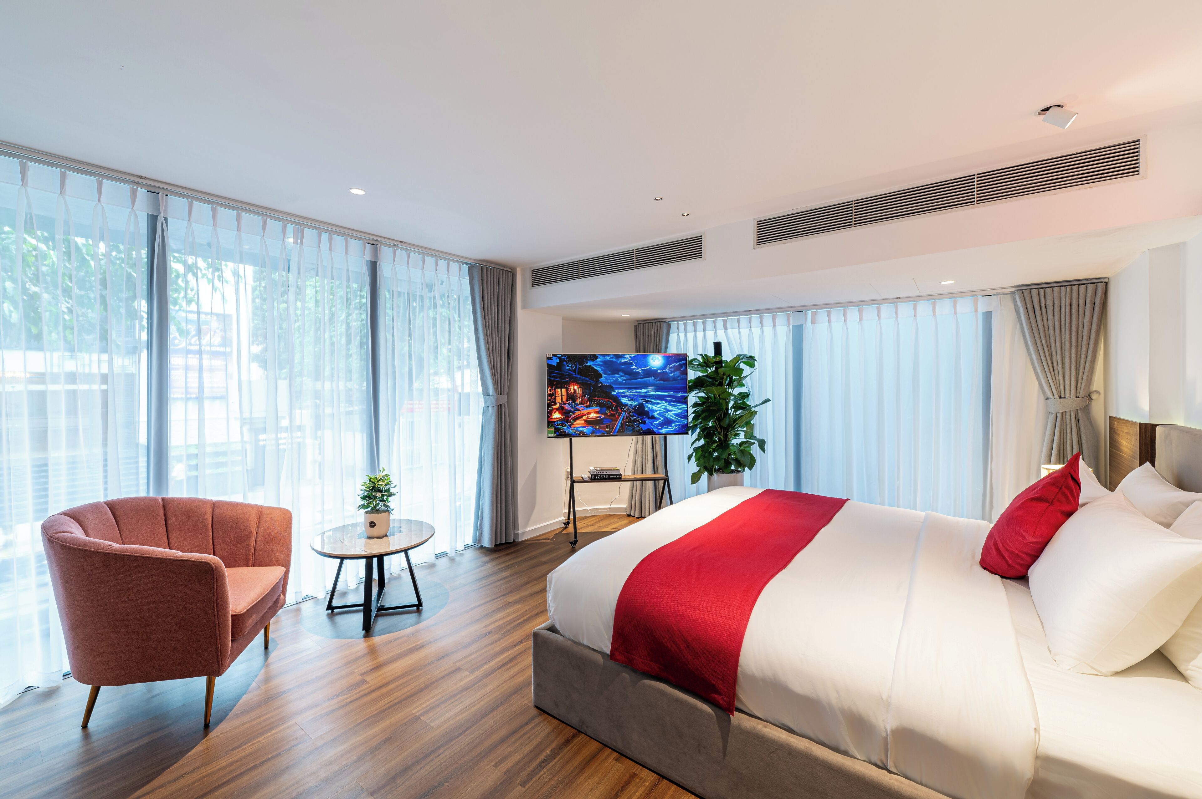 Une chambre d’hôtel moderne avec un grand lit, un canapé, une télévision et une petite table.
