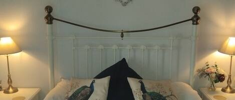 Ein Bett mit dekorativen Kissen, einem weißen Kopfteil und Wanddekorationen, darunter Herzen und ein LOVE-Schild.