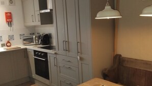 A modern kitchen with grey cabinets, a stove, and a dining table with a unique centerpiece. - Cosy Romantic Cottage with Parking a short drive from the North Lakes & Pennines (Penrith)