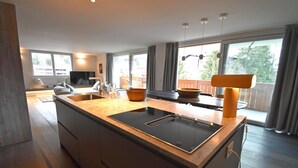 Una cocina moderna con una isla central, electrodomésticos integrados y ventanas amplias.