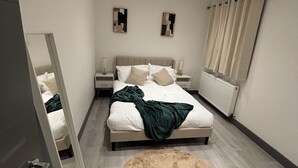 A modern bedroom with a bed, nightstands, a mirror, a fluffy rug, and a radiator. - Stylish 1 Bedroom Apartment in East Croydon - Fast Link To Gatwick Airport (Croydon)