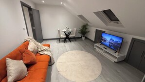 A modern living room with a sofa, TV, and dining area. - Stylish 1 Bedroom Apartment in East Croydon - Fast Link To Gatwick Airport (Croydon)