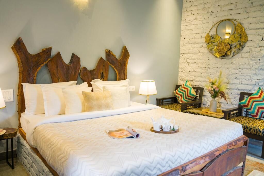 A bed with a wooden headboard, white bedding, and a bedside table with a lamp and decorative pillows.