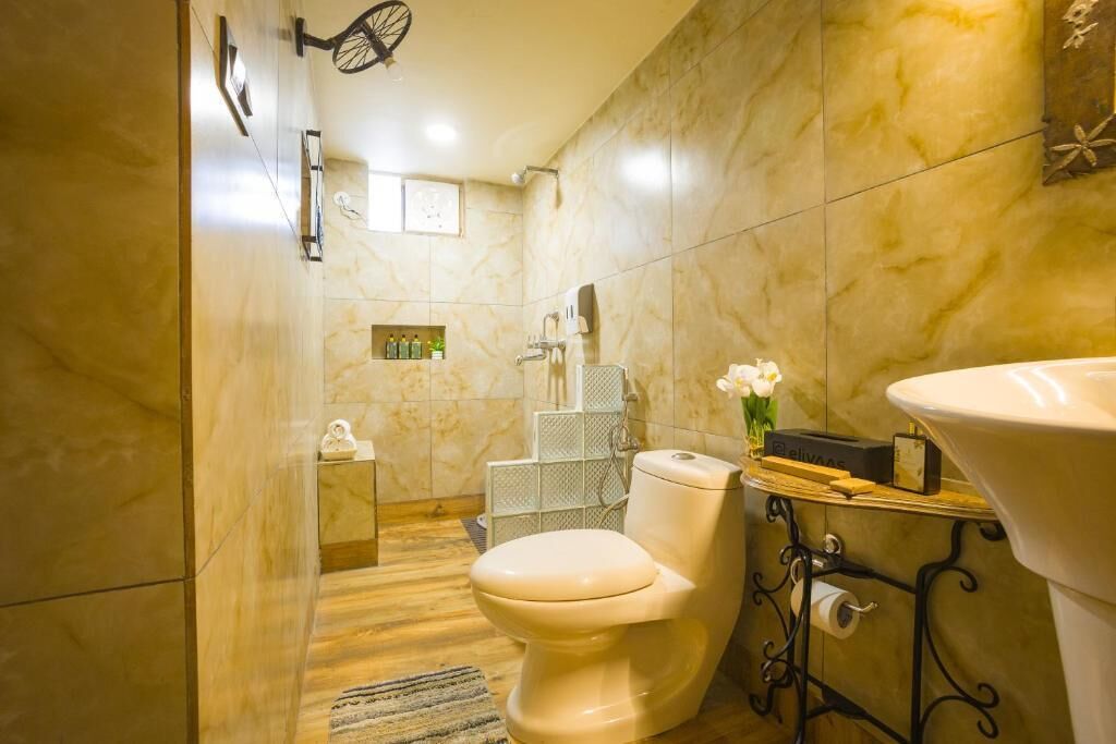 Une salle de bain avec des toilettes, un lavabo, une douche et un mur en marbre.