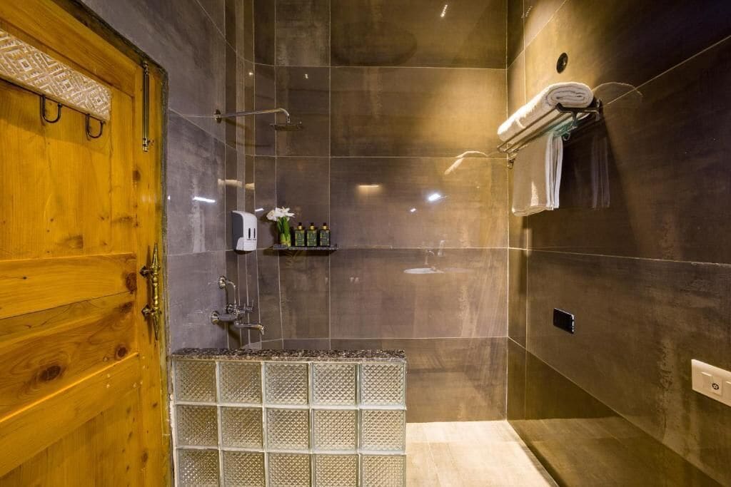 A modern shower area with a wooden door, a glass shower enclosure, and a towel rack.
