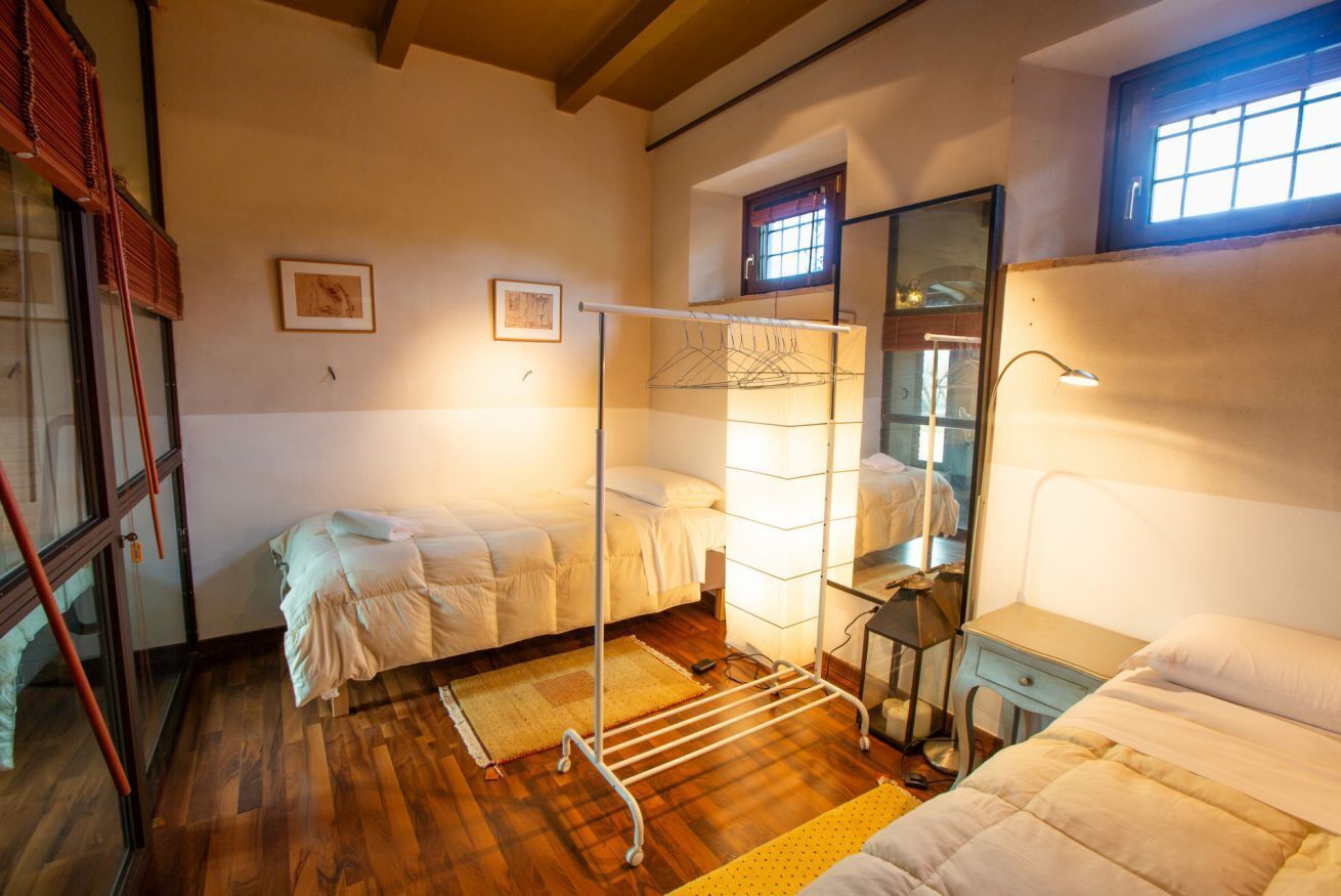 Ein Schlafzimmer mit zwei Betten, einem Wäscheständer, einem Spiegel und einem Fenster.