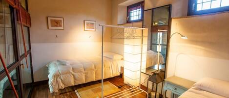 Un dormitorio con dos camas, un tendedero, un espejo y una ventana.