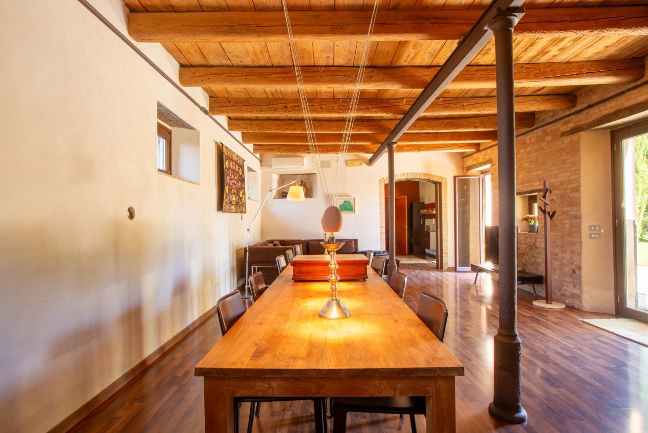 A spacious dining area with a long wooden table, chairs, and a hanging light fixture.
