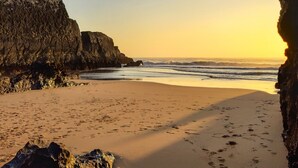 A beach with rocky cliffs and a clear sky.