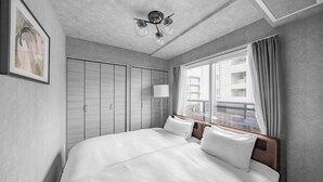 Habitación de hotel moderna con una cama grande, ventilador de techo, ventana con cortinas e imagen enmarcada en la pared.