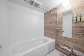 A modern bathroom with a white bathtub, a wooden wall panel, a mirror, and a shelf with toiletries. - BLUE FOREST 203 (Sapporo)