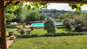 Un espace piscine agrémenté d’une pergola, d’un petit jardin et offrant une vue sur le paysage environnant.