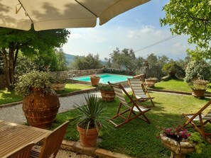 A poolside area with a wooden deck, lounge chairs, and potted plants. - B&B Villa Lucchese, portion of private villa in the hills of Lucca (Arsina)