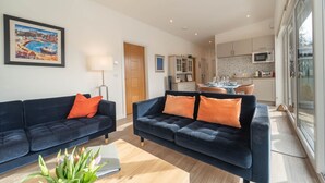 Ein modernes Wohnzimmer mit zwei dunklen Sofas, einem Couchtisch und einem Gemälde an der Wand.