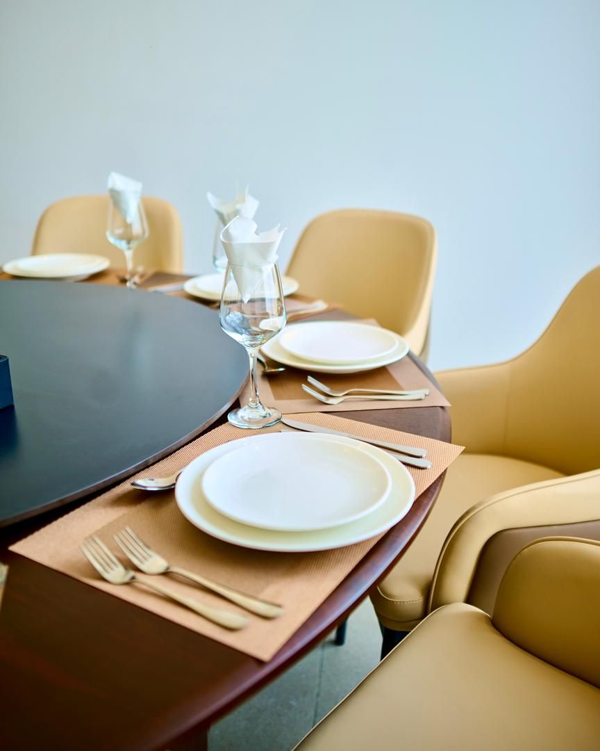 A dining table set with plates, cutlery, and a glass.