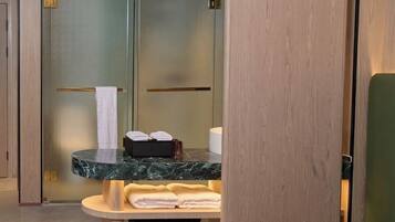 Un baño moderno con lavamanos de mármol, un perchero y una cesta de mimbre.