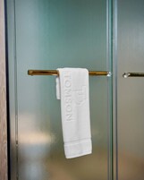 A white towel hanging on a gold towel bar with the word 'TONSON' embossed on it.
